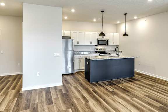 A kitchen with a black counter top and wooden floors.