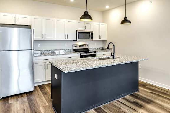 A kitchen with a black island and stainless steel appliances.