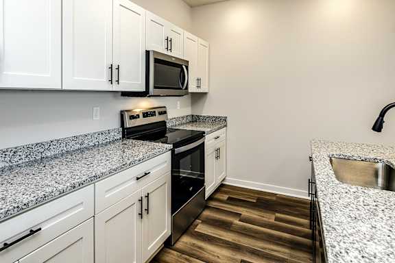 A kitchen with white cabinets and a granite countertop.
