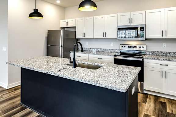 A kitchen with a granite countertop and black cabinets.