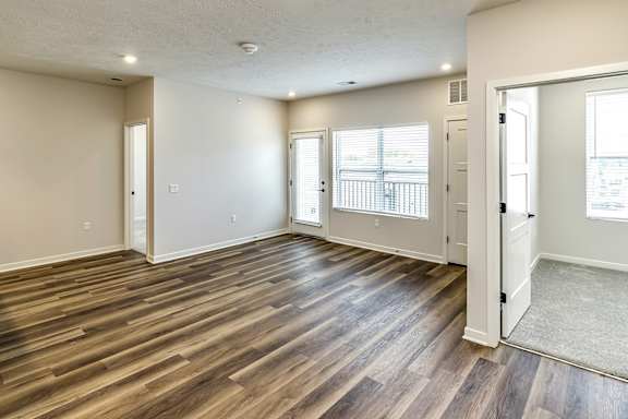 A room with wooden flooring and a balcony with a railing.