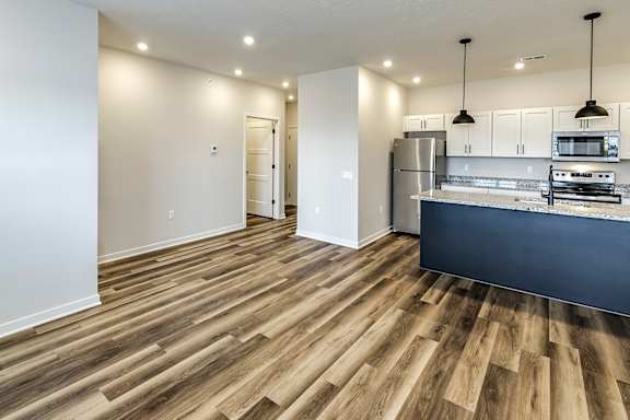 A kitchen with a refrigerator, microwave, and oven.
