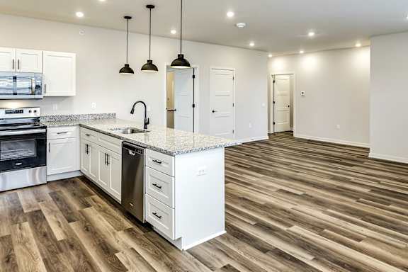 A kitchen with white cabinets and a wooden floor.