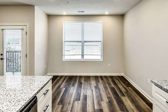 A kitchen with a granite countertop and wooden flooring.