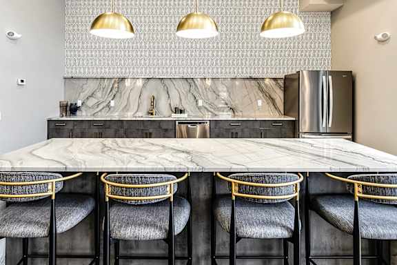 A kitchen with a marble countertop and bar stools.