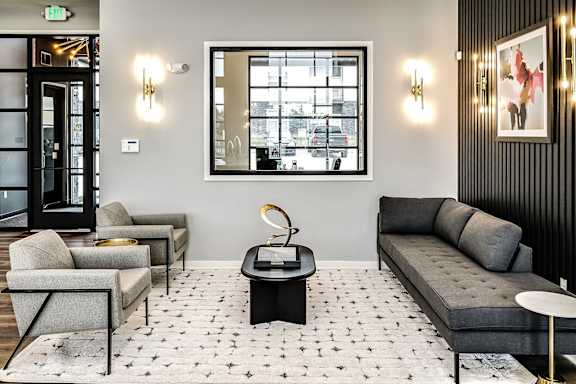 A living room with a grey couch, a coffee table, and a large window.