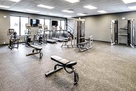 A gym with a variety of equipment including treadmills, weight machines, and benches.