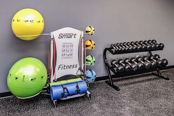 A Smart Fitness sign is displayed on a stand in a gym with exercise equipment.