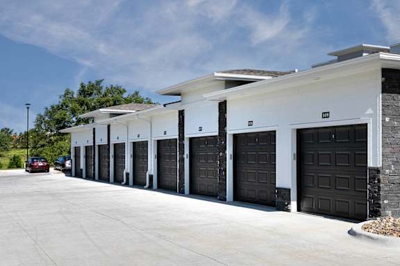 A row of black garage doors in front of a white building.