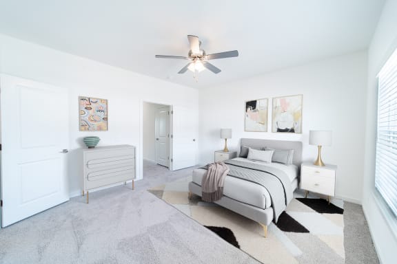 a white bedroom with a bed and a ceiling fan
