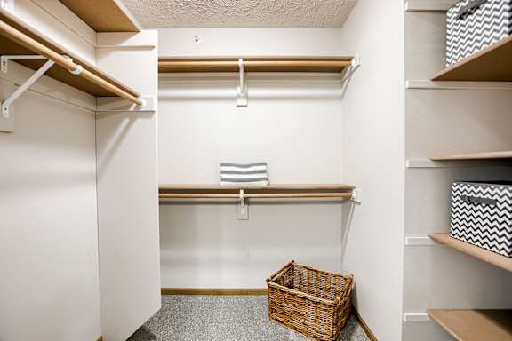 A small closet with a basket on the floor.