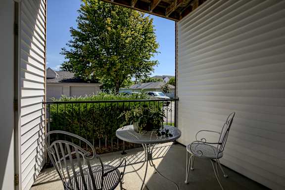 A patio with a table and chairs overlooking a garden.