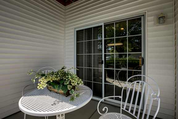 A white table with a plant on it sits on a porch.