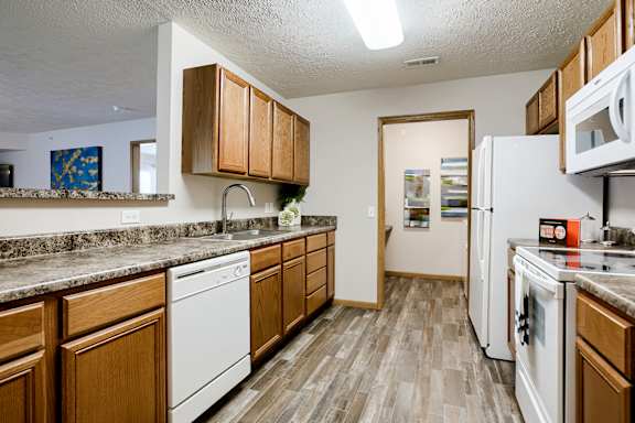 A kitchen with white appliances and wooden cabinets.