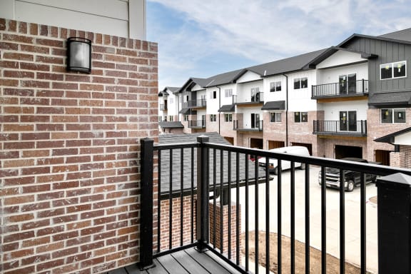 a balcony with a brick wall and a black railing