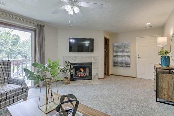 A living room with a fireplace and a flat screen TV mounted above it.
