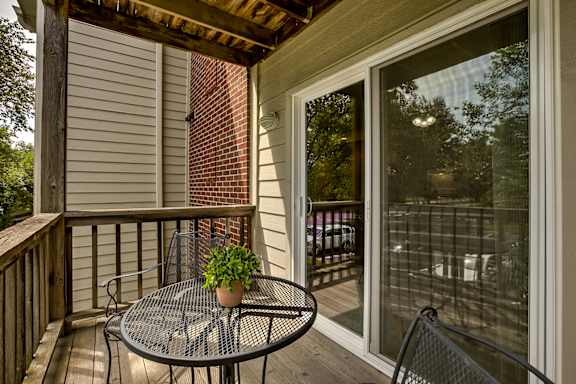 A small table with a plant on it is on a balcony.