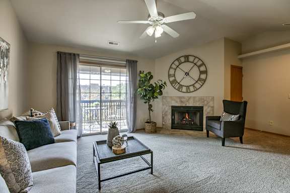 A living room with a fireplace and a ceiling fan.