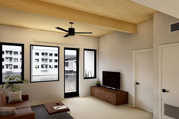 A living room with a brown couch, a coffee table, a flat screen TV, and a ceiling fan.