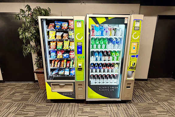A yellow and black vending machine with a variety of snacks and drinks.