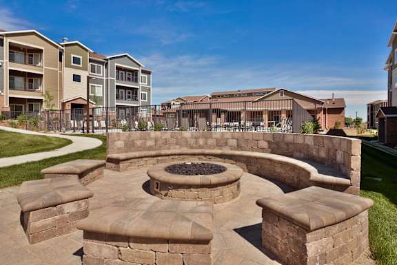 A fire pit sits in the middle of a stone patio.