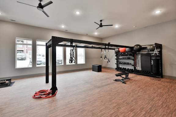 A gym room with a weight rack and a red kettlebell on the floor.