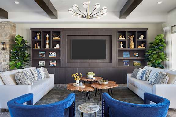 A modern living room with a white couch, a coffee table, and a large TV mounted on the wall.