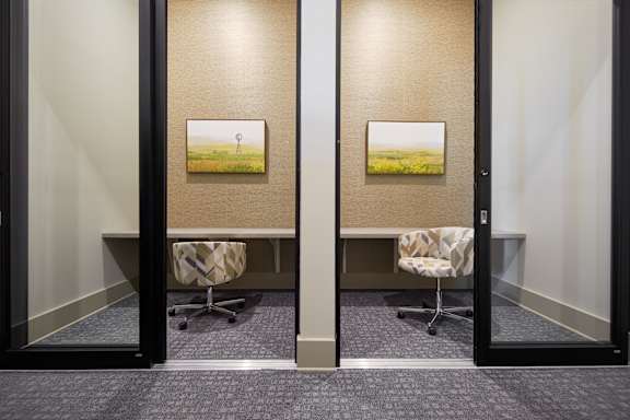 Two chairs are in front of two pictures of a field with a pole in the middle.