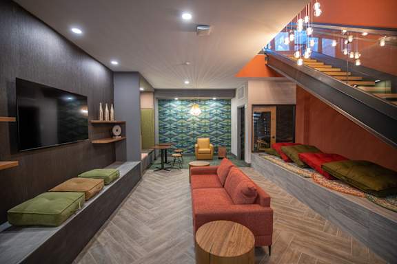 A modern living room with a staircase and a green wallpapered area at Cityplace Apartment Homes Apartments, Allentown, PA, 18101