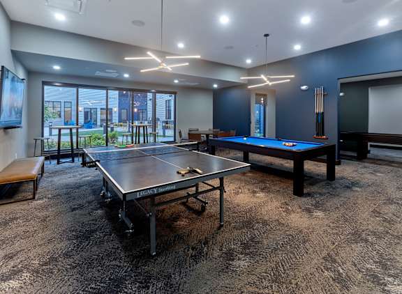 A room with a pool table and ping pong table.