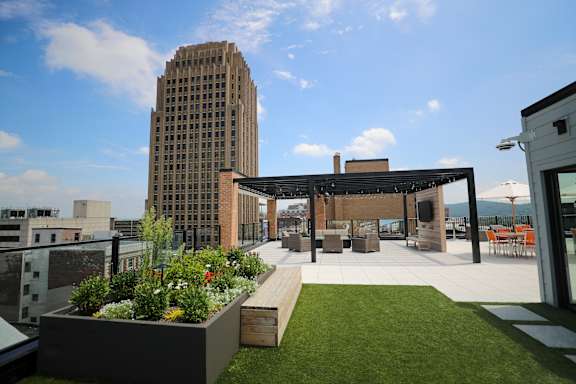 A rooftop patio with a table and chairs and a tall building in the background at Cityplace Apartment Homes Apartments, Allentown, PA, 18101