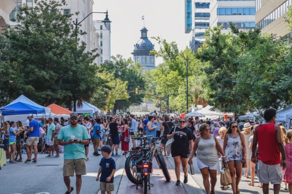 A busy street scene with people walking and a child on a bicycle. at The Lady, South Carolina