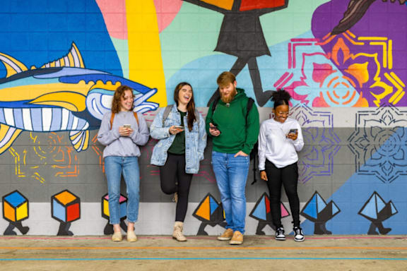 people standing in front of a wall with their cell phones