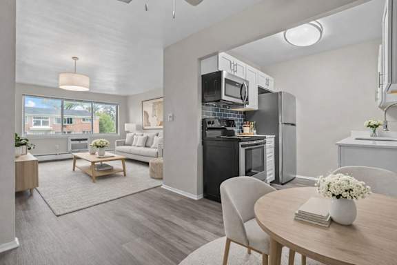 A modern kitchen with a dining table set with a vase of flowers and a book. at Plymouth Heritage - Plymouth, MI, MI, Plymouth, MI