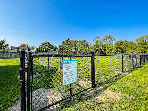 A sign on a fence reads "DOG PARK RULES".