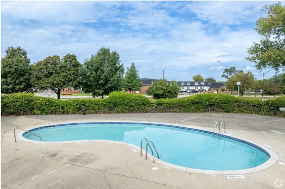A small pool surrounded by greenery and a cloudy sky.