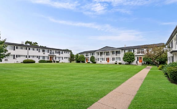 A long grassy area in front of a building with a pathway leading to it.