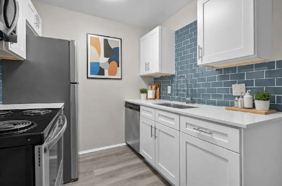 A modern kitchen with a black stove top oven and white cabinets.