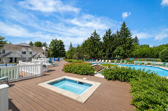 A wooden deck with a pool and lounge chairs.