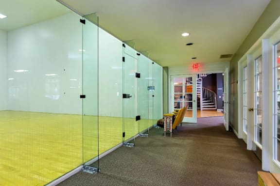 A hallway with a yellow floor and glass walls.
