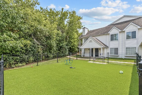 A white house with a green lawn and a playground in front.