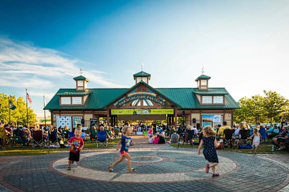 A group of people are dancing in front of a building with a green roof.