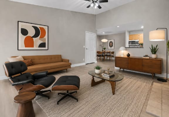 A living room with a brown sofa, black chairs, and a coffee table.