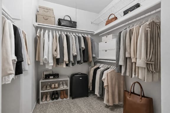 A white closet with clothes and shoes.