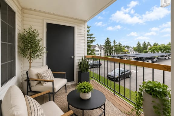 A balcony with a table and chairs overlooking a parking lot.