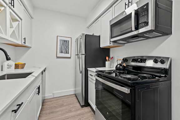 A modern kitchen with a black stove and white cabinets.