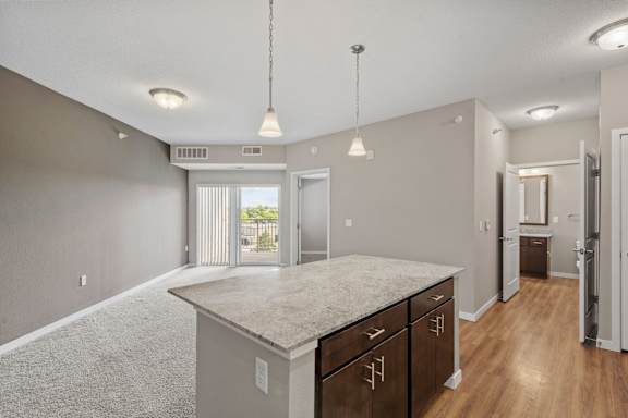 A spacious kitchen with a granite countertop and wooden cabinets.