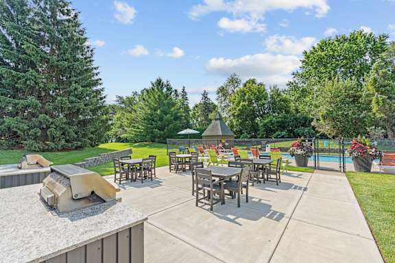 A patio with a table and chairs is surrounded by trees.