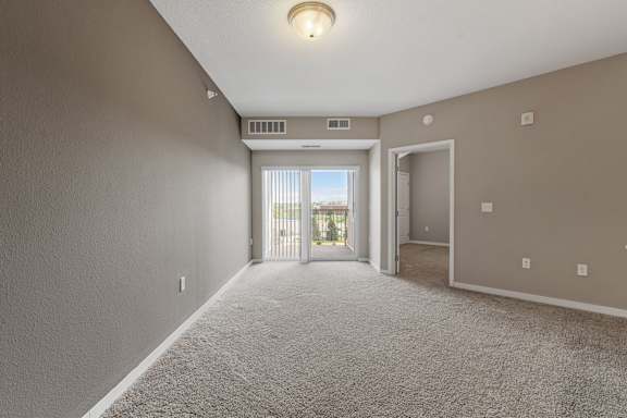 A room with a carpeted floor and a window with blinds.