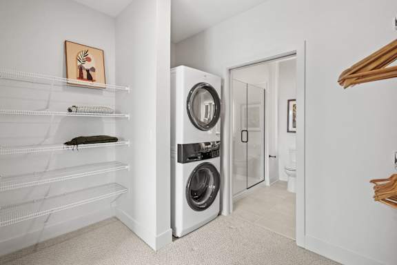 A white laundry room with a washer and dryer built into the wall.